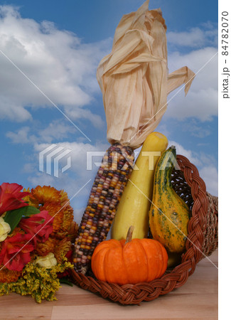 Cornucopia With Fall Vegetables and Flowers on Blue Sky Background Cornucopia With Fall Vegetables and Flowers on Blue Sky Background 84782070