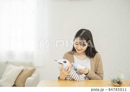 哺乳瓶で赤ちゃんにミルクを飲ませる女性(笑顔) 哺乳瓶で赤ちゃんにミルクを飲ませる女性(笑顔) 84785011