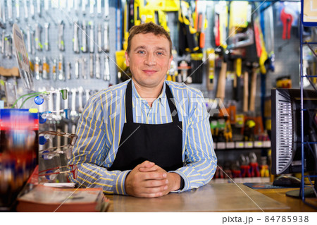 Positive seller standing in hardware shop 84785938