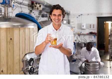 Man brewer in uniform is standing with glass of two type of beer 84786132