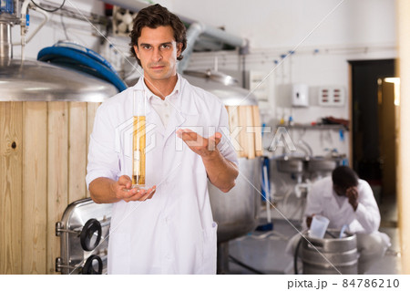 Young man brewer controlling quality of beer in flask in brew-house Young man brewer controlling quality of beer in flask in brew-house 84786210