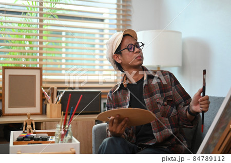 Asian man artist painting with watercolor at home. 84789112