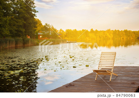 Wooden dock with lounge chair on pier on the calm lake in the middle of the forest 84790063