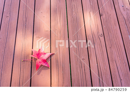 木目のテーブルの上にあるモミジバフウの赤い葉　秋のイメージ 84790259