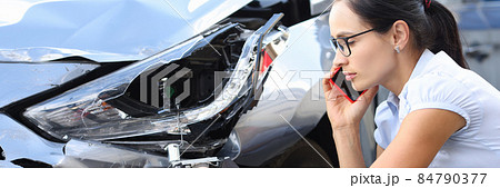 Woman driver is talking on phone next to wrecked car closeup 84790377