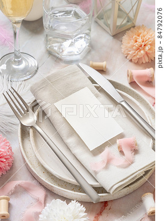 Wedding Table place with a card over napkin near flowers, silk ribbons and feathers, mockup 84792076