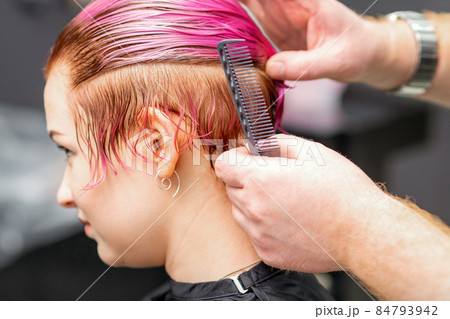Styling female hair. Male hairdresser makes hairstyle for a young woman in a beauty salon. Styling female hair. Male hairdresser makes hairstyle for a young woman in a beauty salon. 84793942