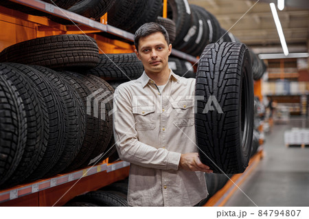 male customer taking new tires in the supermarket. 84794807