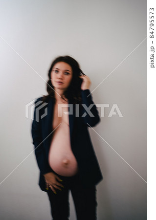 defocus beautiful pregnant woman in a black jacket with bare breasts and a belly 84795573