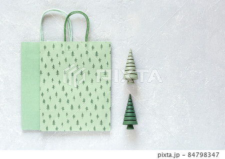 Green paper Christmas bags and wooden Christmas trees on grey background Green paper Christmas bags and wooden Christmas trees on grey background 84798347