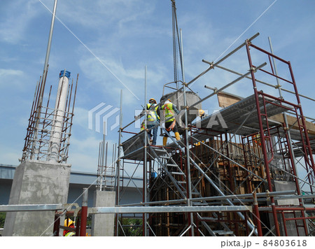JOHOR, MALAYSIA -MARCH 13, 2016: A group of construction workers pouring concrete using concrete bucket into the column form work at the construction site.   84803618