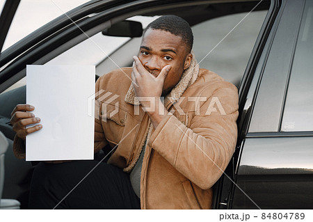 Black man with a confused face impression holding sheet of paper Black man with a confused face impression holding sheet of paper 84804789