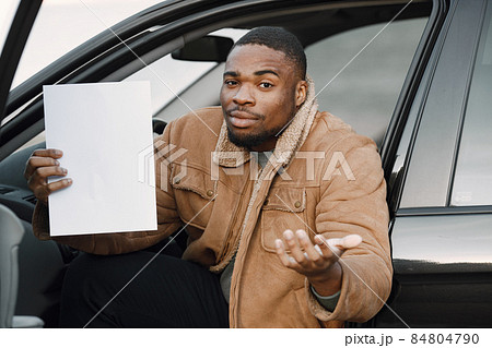 Black man with a confused face impression holding sheet of paper 84804790