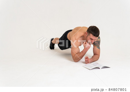 Bodybuilder reads the book on a white background isolated at the bottom of his head on his hands bodybuilder young muscle reader healthy, standing. manager biceps, posing tan Bodybuilder reads the book on a white background isolated at the bottom of his head on his hands bodybuilder young muscle reader healthy, standing. manager biceps, posing tan 84807801