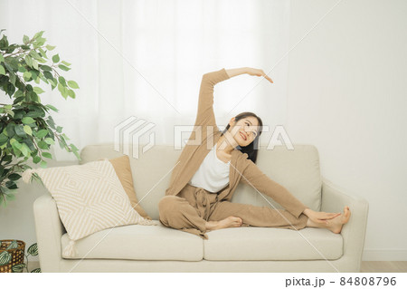 ソファでストレッチする女性（腕・肩） 84808796