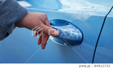 Woman closes automobile driver door covered with rain drops Woman closes automobile driver door covered with rain drops 84812732