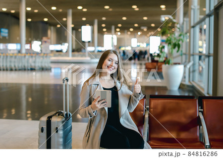 Woman using internet by tablet in airport hall near valise and s 84816286