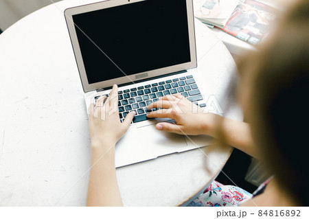Blurry girl working with laptop, focus on computer. 84816892