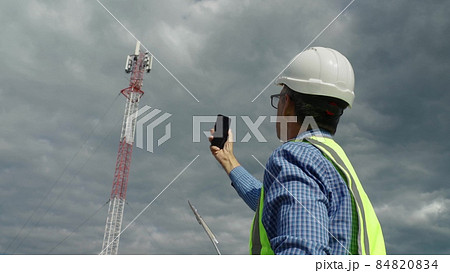 Telecommunications engineer checking the signal from a telecommunications tower. Telecommunications engineer checking the signal from a telecommunications tower. 84820834