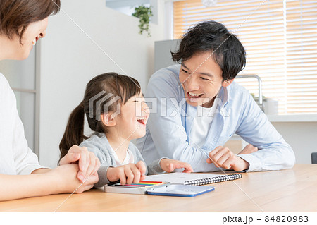 リビングでお絵描きをしながら笑う上前歯の抜けた小学生の女の子とパパ 84820983