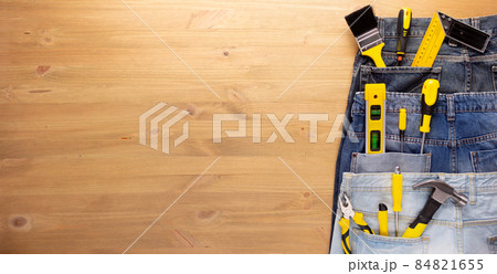 Kit of tool in jeans pocket at wooden table background. House renovation concept 84821655