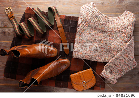 Leather boots with sweater and female clothes at wood table. Travel concept of retro clothing Leather boots with sweater and female clothes at wood table. Travel concept of retro clothing 84821690