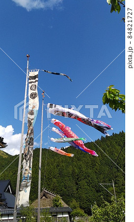 青空と山を背景に泳ぐ鯉のぼり、お父さん鯉、お母さん鯉、子供の鯉三匹