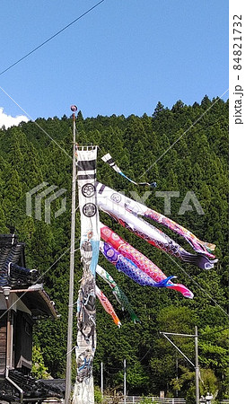 青空と山を背景に泳ぐ鯉のぼり、お父さん鯉、お母さん鯉、子供の鯉三匹