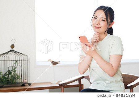 椅子に座ってスマホを操作する女性 84821834
