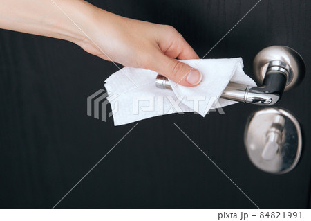 Cleaning black door handles with an antiseptic wet wipe. Sanitize surfaces prevention in hospital and public spaces against corona virus. Woman hand using towel for cleaning home room door link. Cleaning black door handles with an antiseptic wet wipe. Sanitize surfaces prevention in hospital and public spaces against corona virus. Woman hand using towel for cleaning home room door link. 84821991