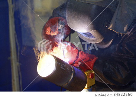 worker welding metal tubes with electrode at a workshop worker welding metal tubes with electrode at a workshop 84822260