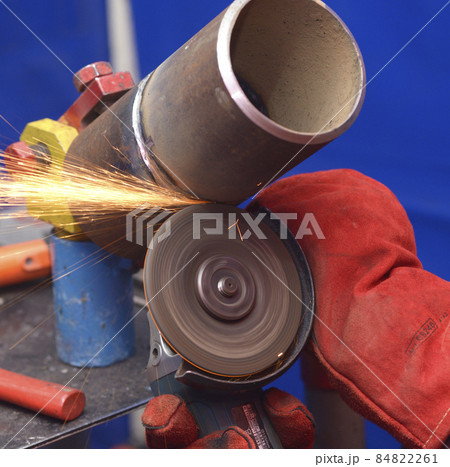 worker hands grinding metal tube with a grinder, preparing for welding worker hands grinding metal tube with a grinder, preparing for welding 84822261