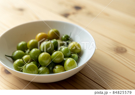 家庭菜園で収穫した、白いお皿に入れてある青いプチトマト 84825579