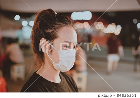 Portrait of young woman wear protection mask with beautiful bokeh in night market 84826351