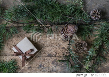 Christmas present box, pine tree branch and cones on wooden table 84826832