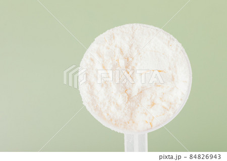 Whey protein powder in measuring spoon close up 84826943