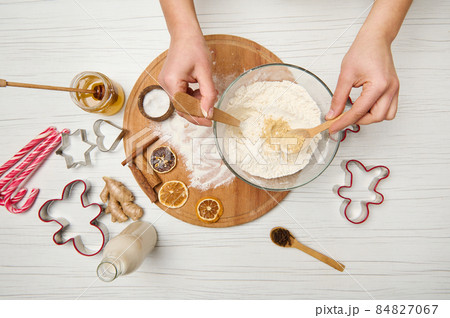 Woman's hands mixing dry ingredients in a bowl of flour while preparing gingerbread dough for Christmas cookies. Food, culinary, celebrating Christmas traditional events 84827067
