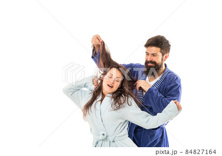 Happy family of man having fun with hair of woman sleeping and yawning in robes, sleepiness 84827164