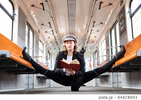 Flexible girl sitting on the split in subway and reading book. Concept of creativity, individuality and self confidence 84828603