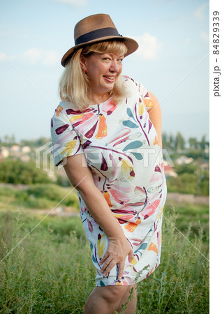 Plus size young woman in dress with hat at nature in the park during summer. Life of people xl size, happy nice natural beauty woman. Concept of overweight, travelling 84829339