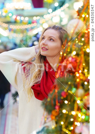 happy blond girl in red scarf close up portrait on decorated Christmas city background 84830347