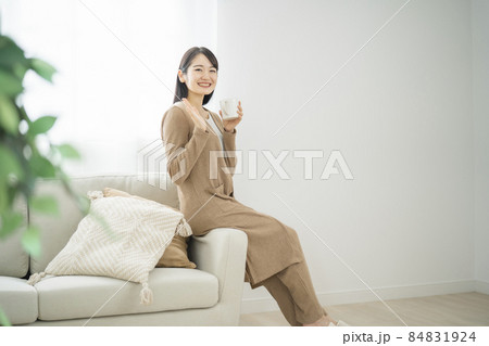 ソファでコーヒーを飲みながら座る女性（同棲・飲み物） 84831924