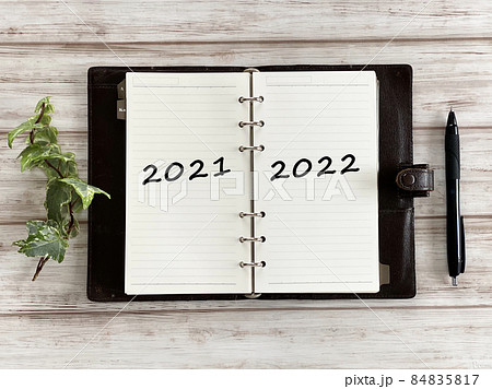 白板の上で開いた手帳とボールペンとツタ_俯瞰_2021と2022文字入り 白板の上で開いた手帳とボールペンとツタ_俯瞰_2021と2022文字入り 84835817