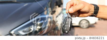 Male hand holding keys near new car closeup 84836221