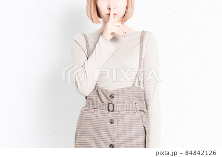白い背景の前に立って、口を隠すポーズをする若い女の子 白い背景の前に立って、口を隠すポーズをする若い女の子 84842126