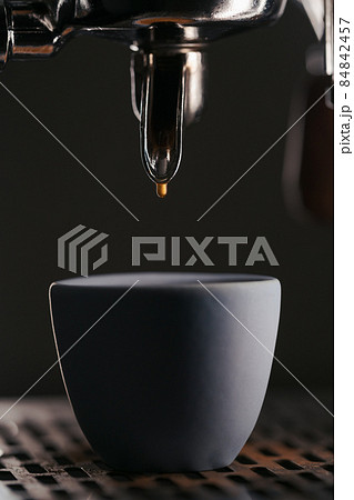 last espresso drop from with single spout portafilter from coffee machine closeup 84842457