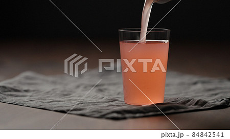 pour guava drink from can into tumbler glass on table 84842541