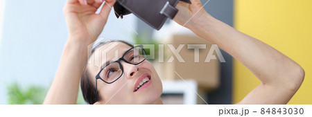 Young woman with glasses looking into empty leather wallet Young woman with glasses looking into empty leather wallet 84843030