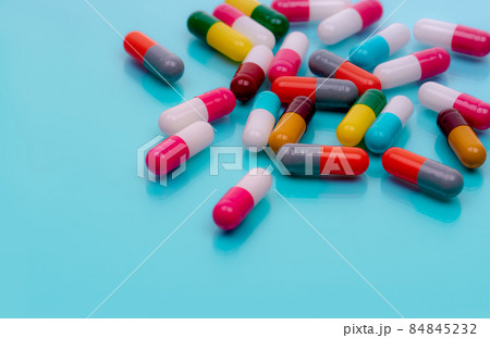 Antibiotic capsule pills on blue background. Prescription drugs. Colorful capsule pills. Antibiotic drug resistance concept. Pharmaceutical industry. Superbug problems. Medicament and pharmacology. 84845232