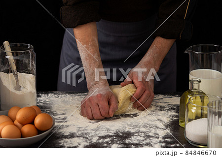 A man baker kneads dough on the table A man baker kneads dough on the table 84846670